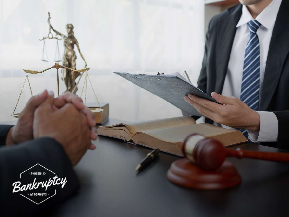 A Phoenix bankruptcy attorney reviews documents with a client, with scales of justice and a gavel in the foreground, symbolizing legal authority and fairness in the bankruptcy process.